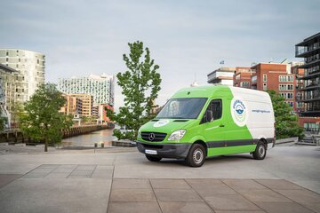Grün-weißer Transporter von Overnight Express & Logistics in der Hamburger HafenCity, im Hintergrund die Elbphilharmonie